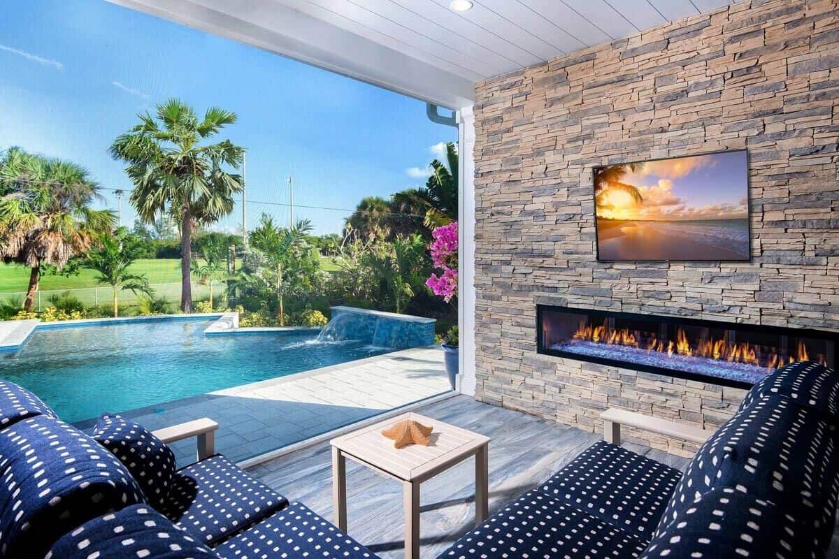 A large fireplace topped with a TV warms the covered lanai.