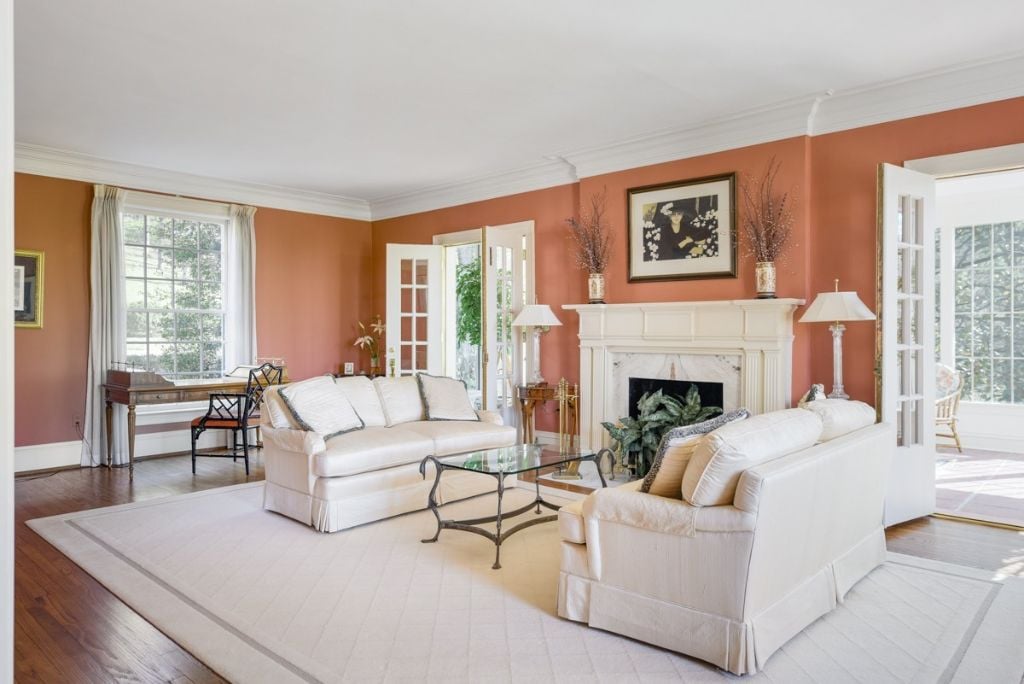 Formal Living Room with elegant fireplace receives abundant light and opens to the sun porch via French doors.