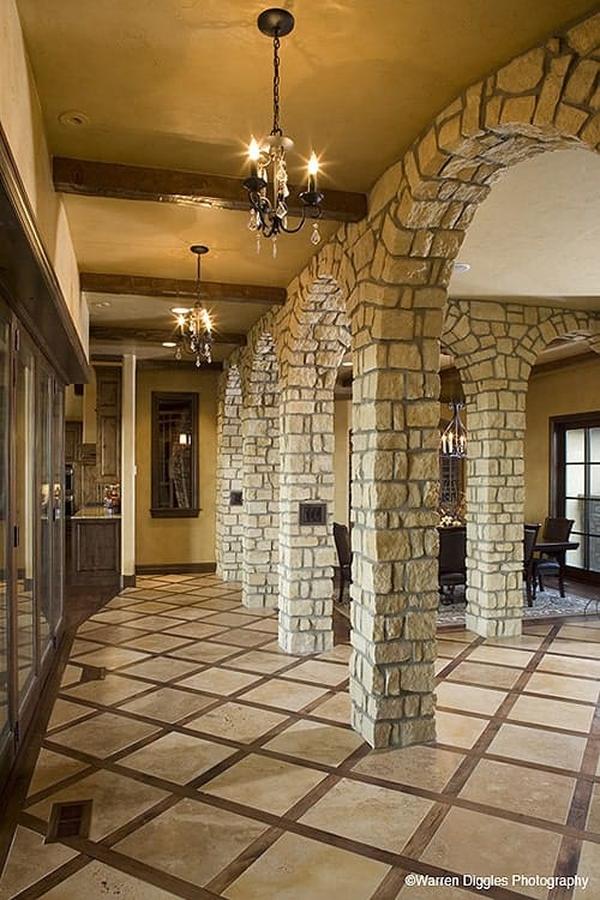 Hallway with brick archways, beamed ceiling, and wrought iron chandeliers.