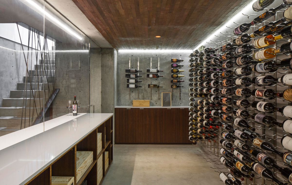 A wine storage area with a tile-topped long table for tasting and a wine rack containing a variety of wines.