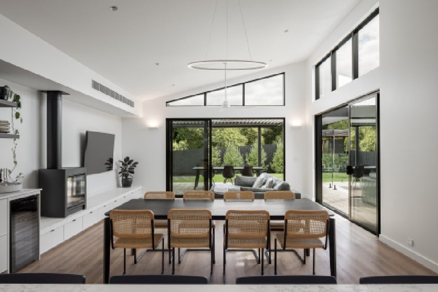 The living and dining area, which features a fireplace and a modern raked ceiling.
