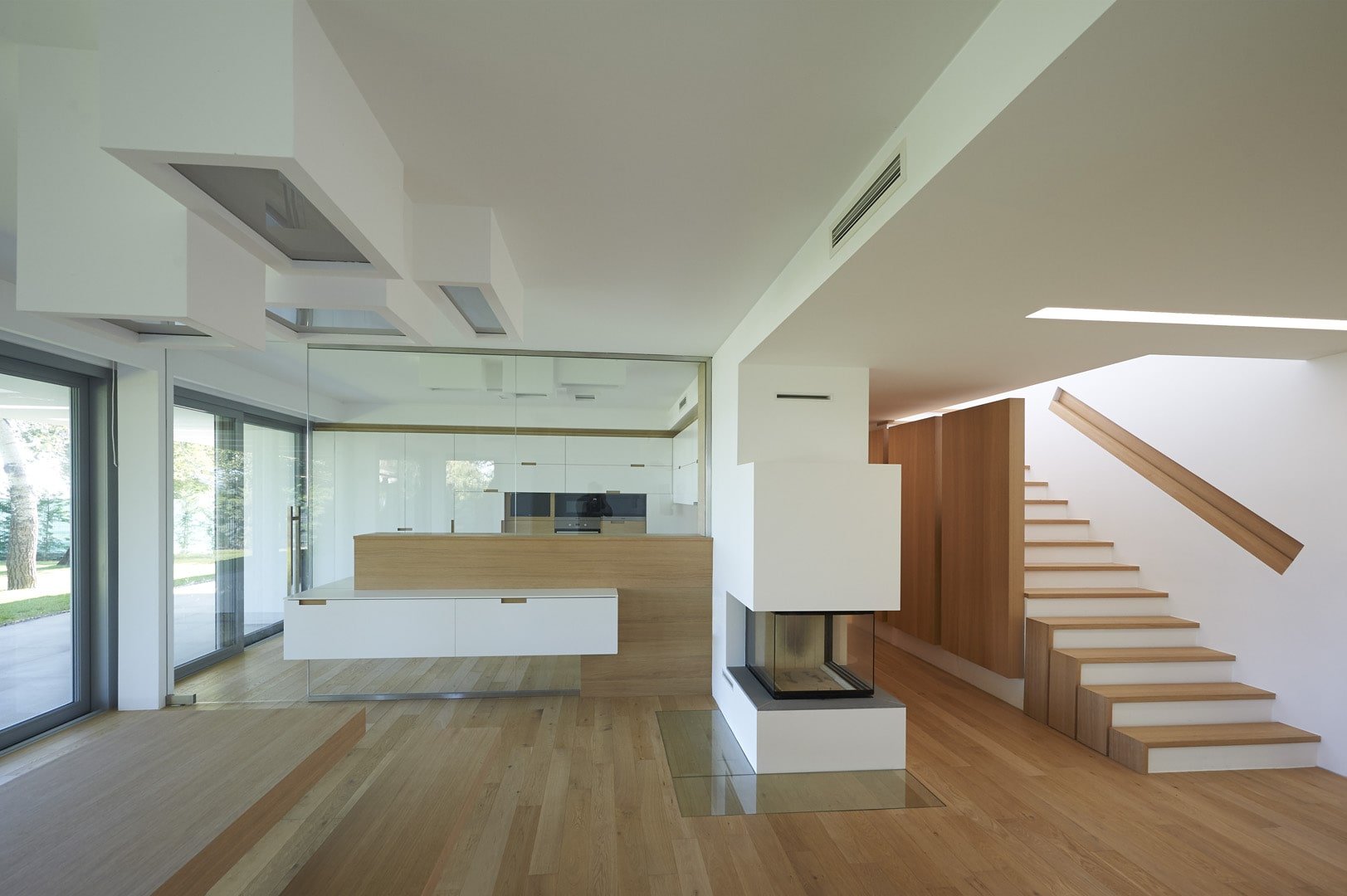 The house's common space, which includes the kitchen with a multi-sided fireplace adjacent to the staircase.