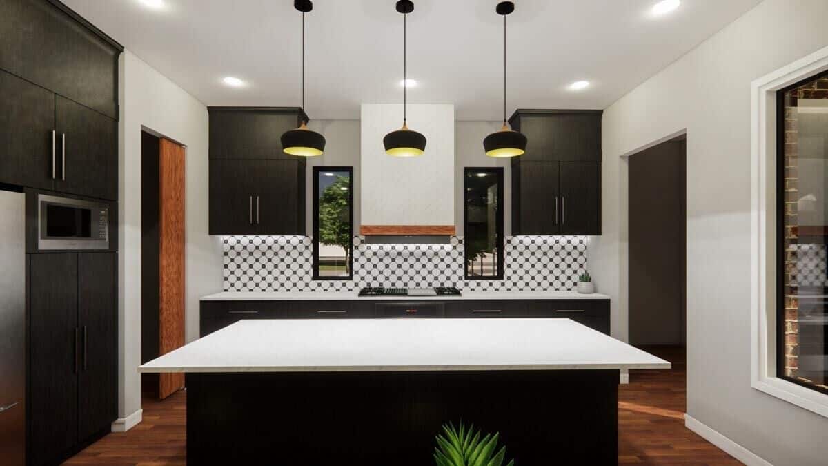 Kitchen with black cabinets, a built-in cooktop, and a center island topped with dome pendants.
