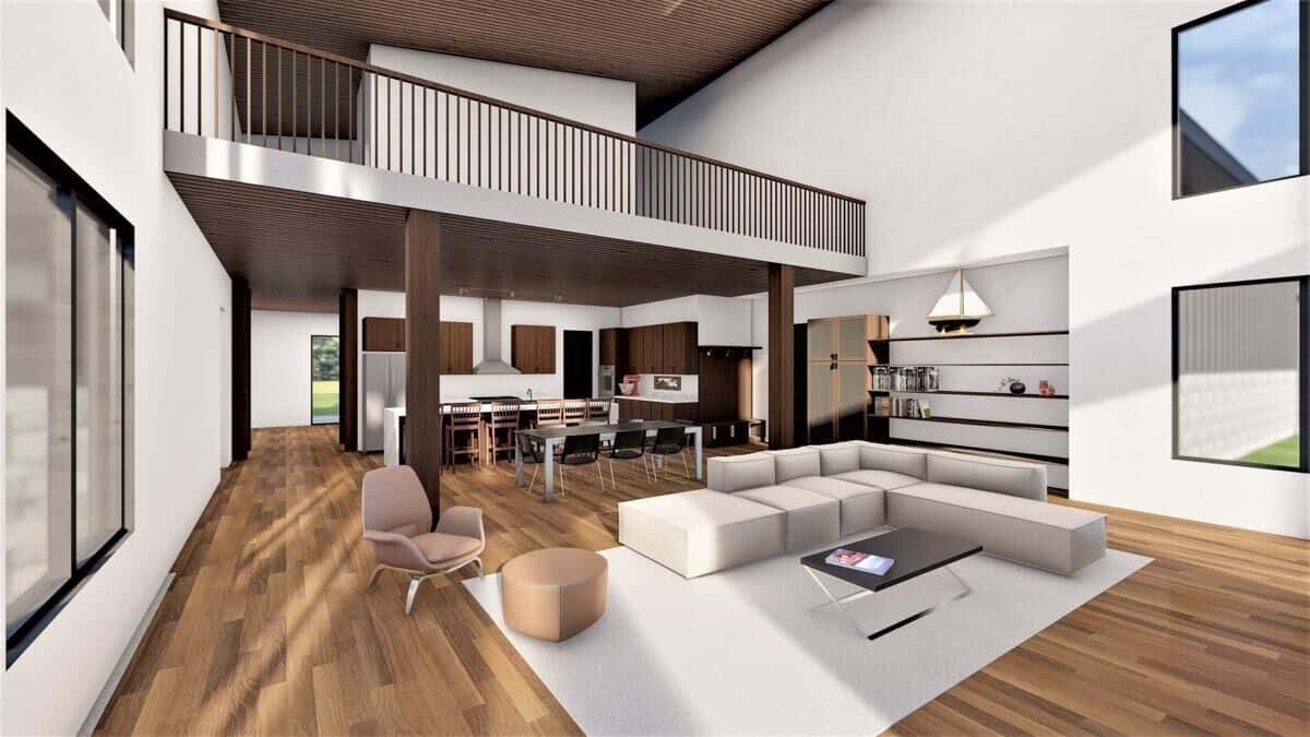 The living room has a tall ceiling, an L-shaped sofa, and a gray area rug that lays on the hardwood floor.
