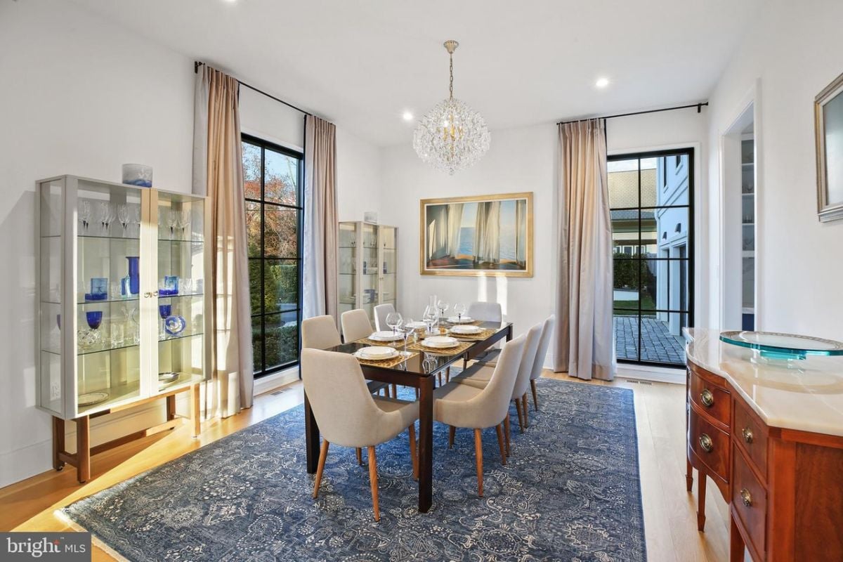 The elegant dining room featured a sleek glass table that shimmered under the glow of a magnificent chandelier, creating a sophisticated and inviting ambiance.