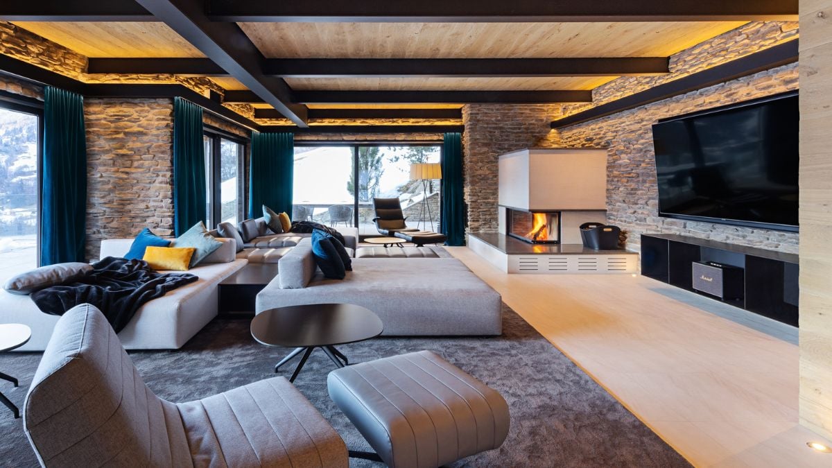 There are many large sofas in the living room, a large flat-screen television, and a fireplace to keep the room warm.