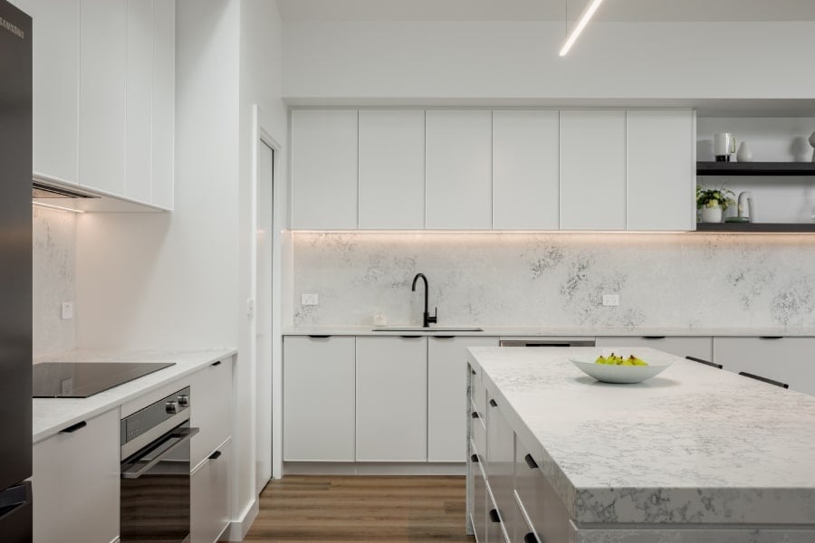 The modern white kitchen design features high-end appliances as well as clean-lined fixtures and materials.