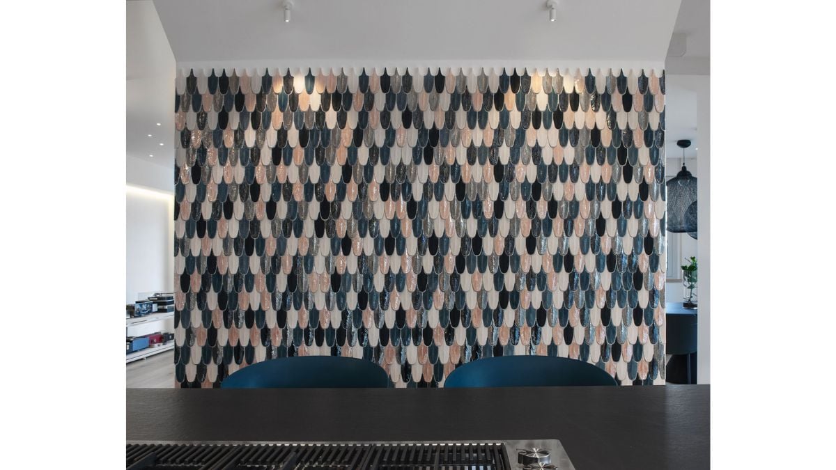 Colors from the island and the living room furniture are matched by a priceless mosaic wall.