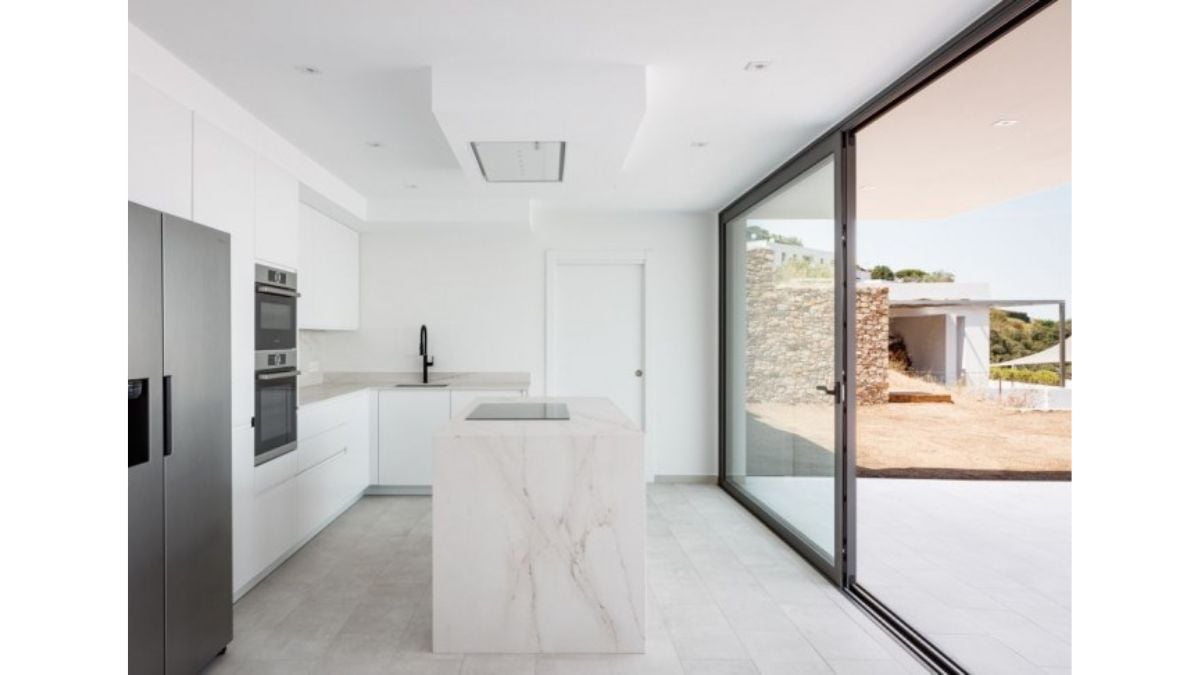 A compact island counter with all-white elements, along with its cabinetry, can be found in the kitchen.