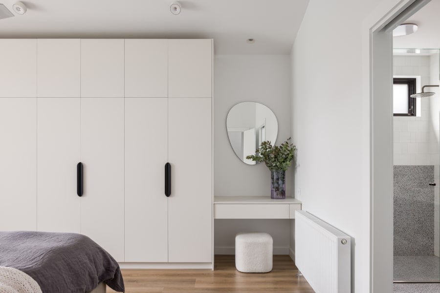 A bedroom with a modern wardrobe and vanity desk.