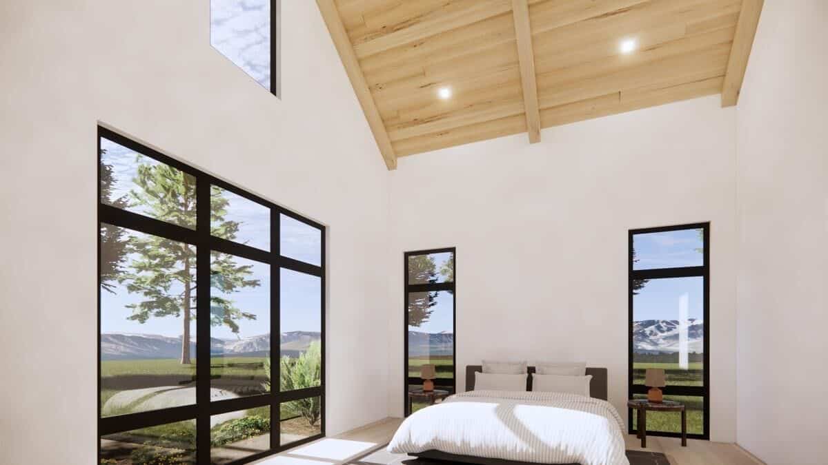 Primary bedroom with a vaulted ceiling and plenty of windows that frame the surrounding landscaping.