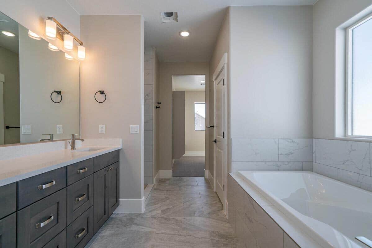 The primary bathroom features a dual sink vanity and a drop-in bathtub clad in white marble tiles.