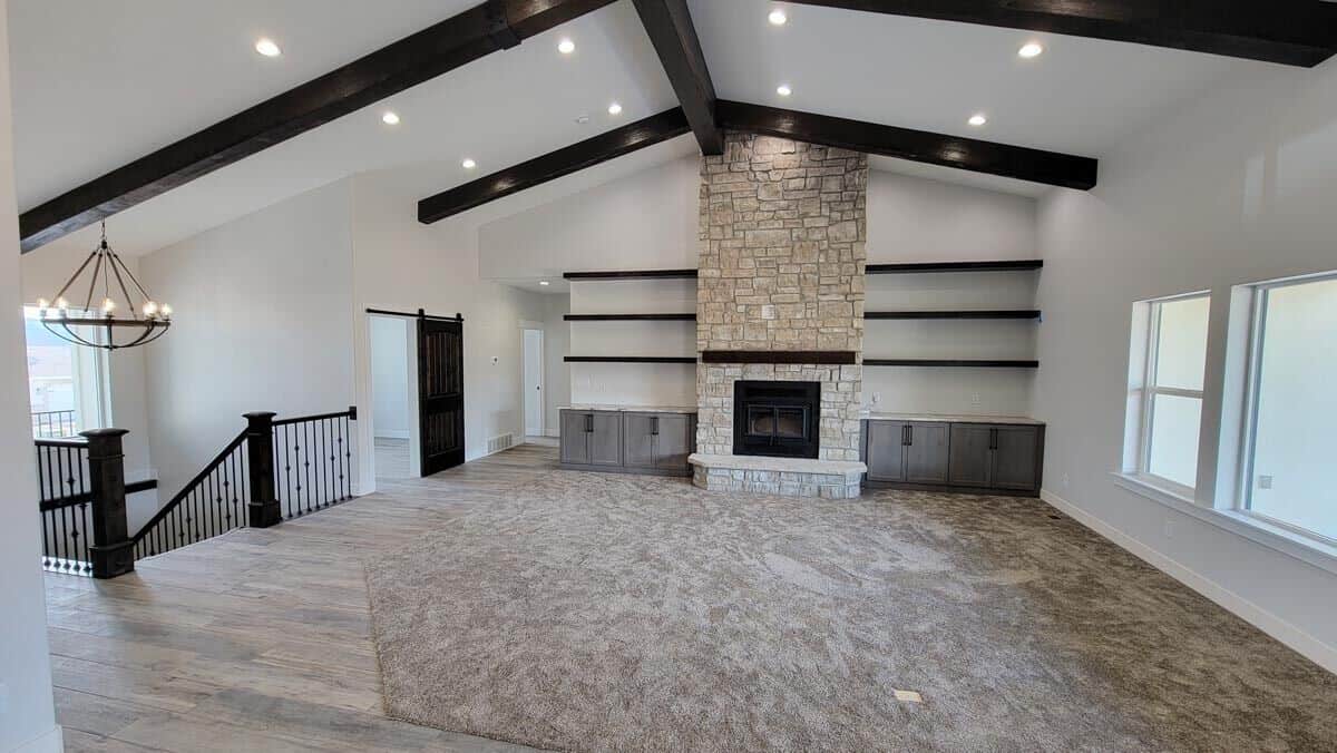 The great room features a cathedral ceiling and a stone fireplace flanked by wooden built-ins.