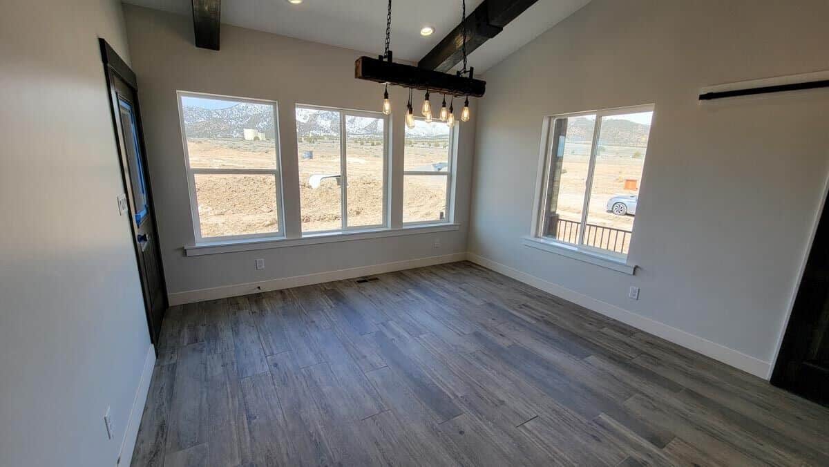 The dining area has a linear chandelier and direct outdoor access.