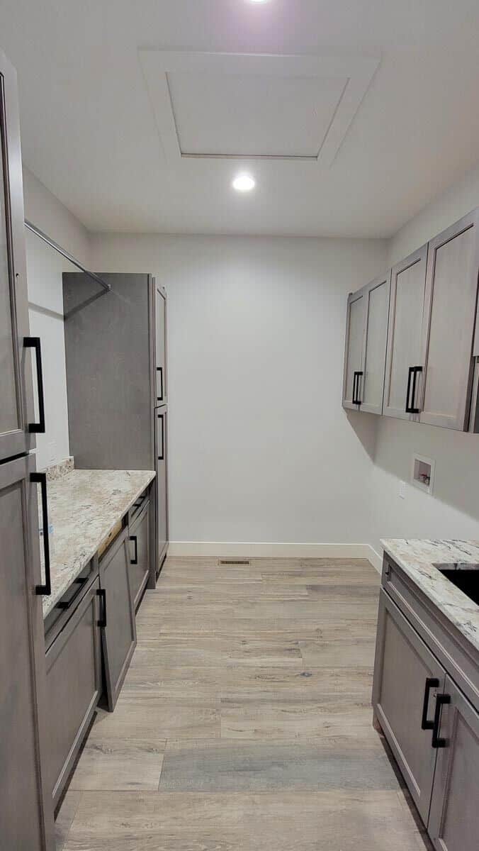 The laundry room offers ample storage, granite countertops, and a utility sink.