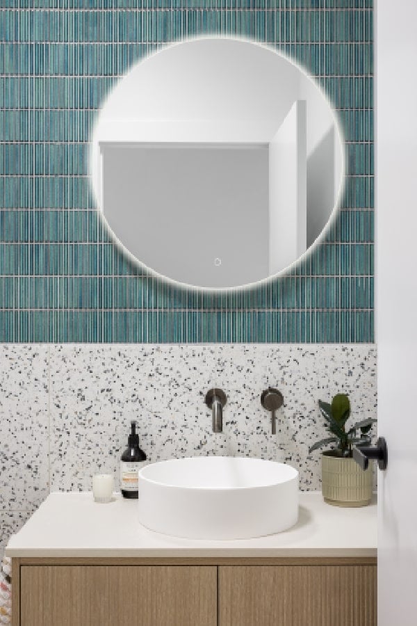 A modern powder room with a round counter-topped sink and mirror.