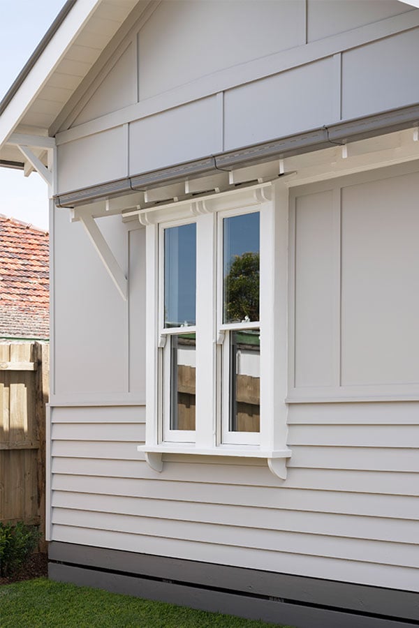 The house's exterior, which has white wooden cladding.