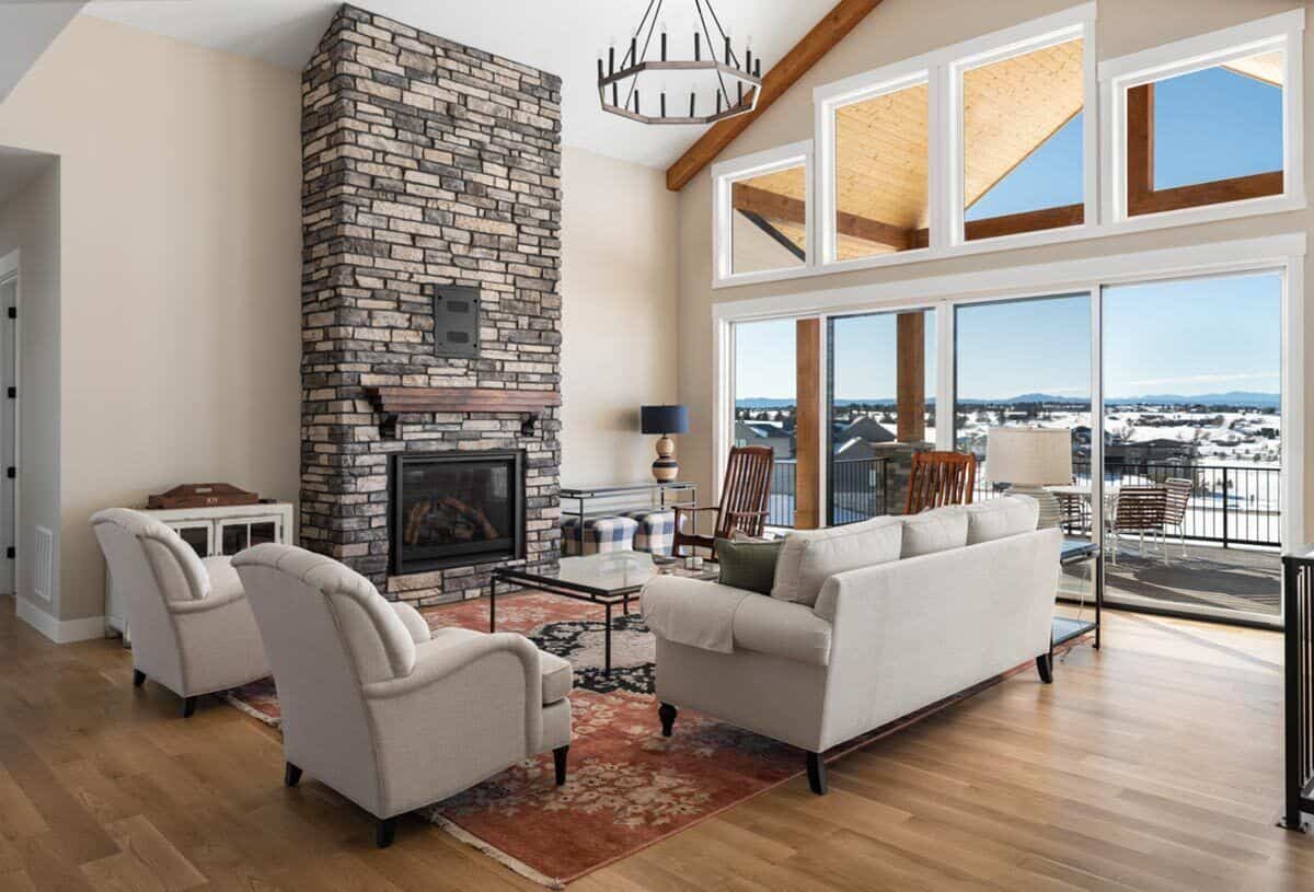 Great room with gray sofas, wooden armchairs, and a stone fireplace.