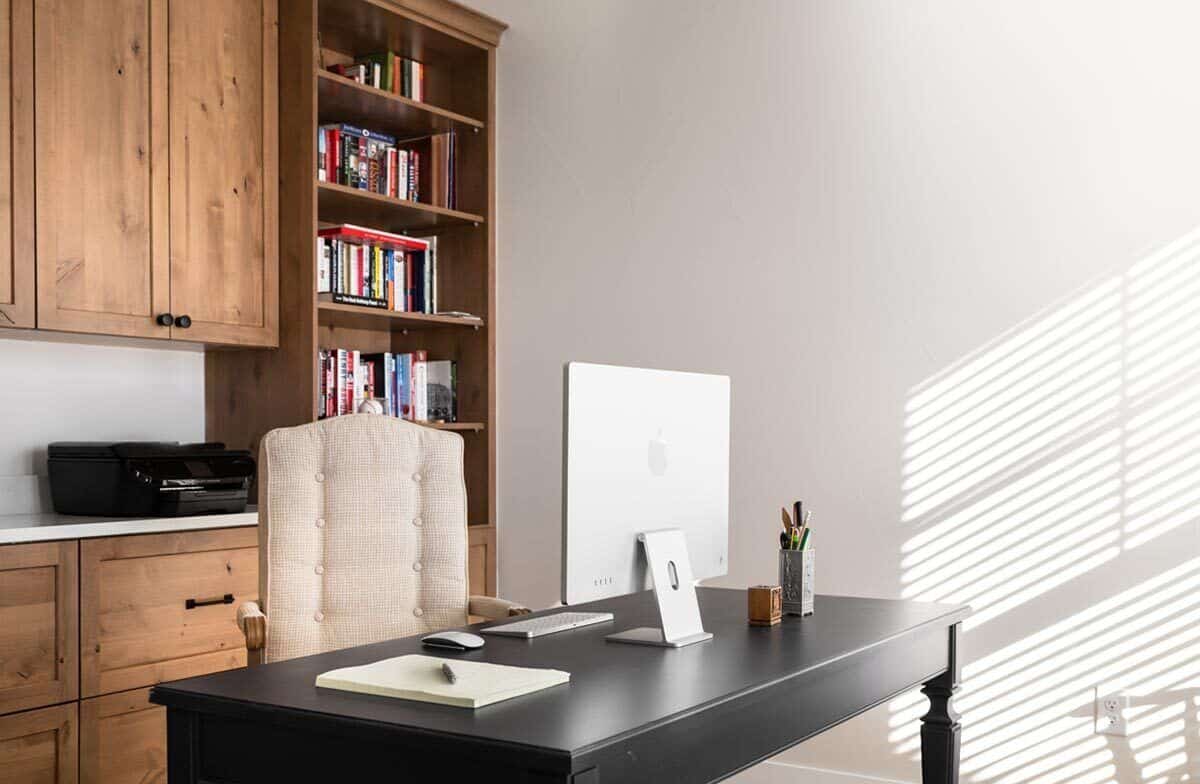 The home office has built-in cabinets and a dark wood desk paired with an upholstered chair.