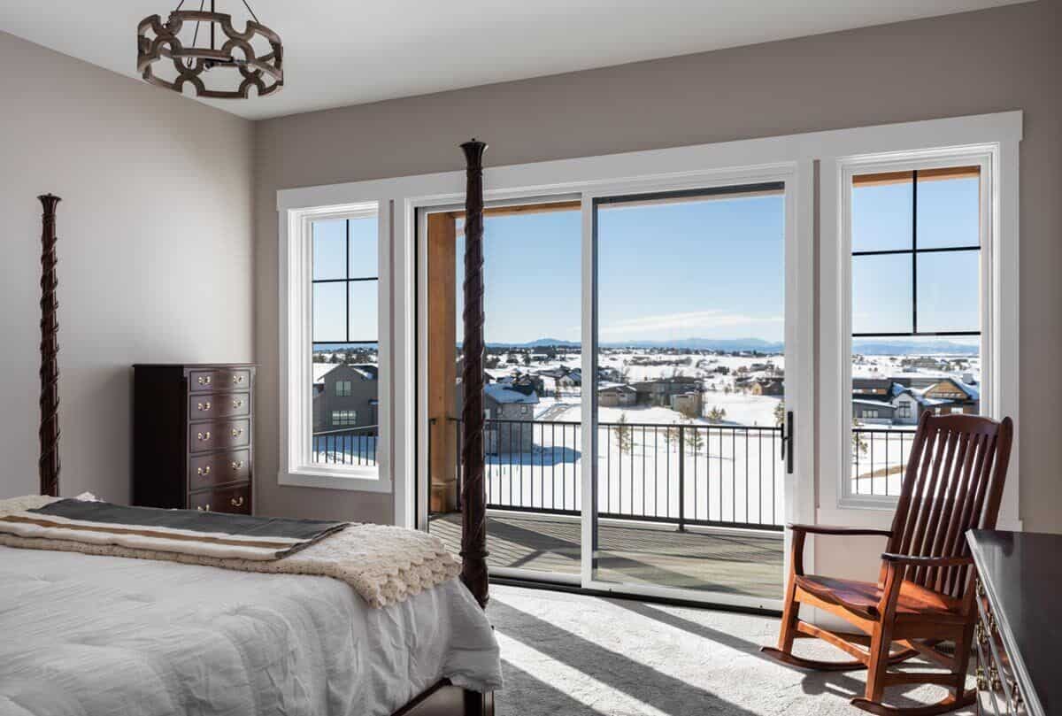 The primary bedroom has a four-poster bed, a wooden rocking chair, and private access to the covered porch.