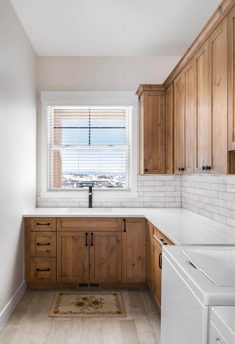 Laundry room with natural wood cabinets, quartz countertops, and a utility sink.