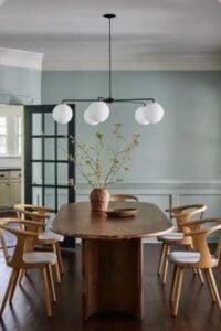 Soft egg-shell blue walls with wainscoting and white crown moulding in this classic mid-century style dining room.