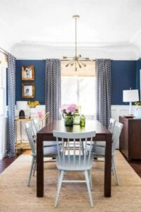 Beautiful cobalt blue walls with white wainscoting is paired with dark wood floors to create a curated transitional dining room.