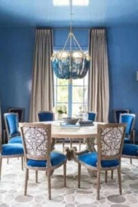 Blue walls and silver drapes adorn the french doors in this Victorian style dining room.