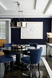 Deep navy and white contrast well together in this lovely dining room. Dark marble floors with a white border really elevate the design along with the wainscot and custom white drapes.