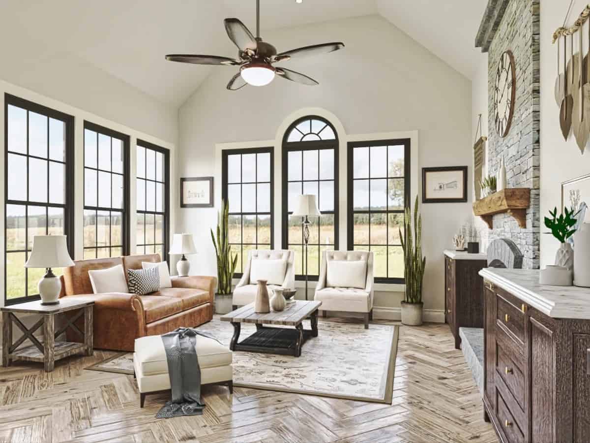 Keeping room with a vaulted ceiling, surrounding windows, and a fireplace lined with a wooden mantel.