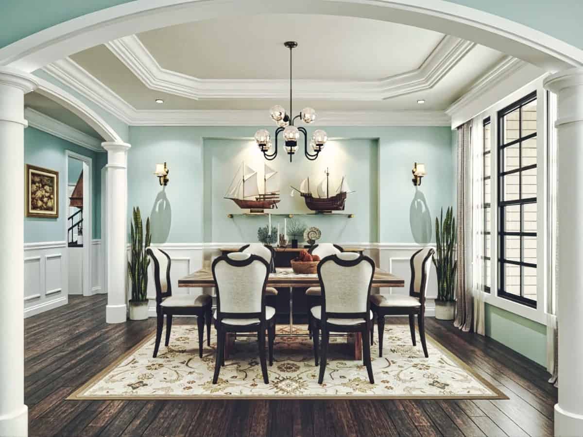 The formal dining room is decorated with half-wainscoted walls, a niche gallery, and a tray ceiling mounted with a glass globe chandelier.
