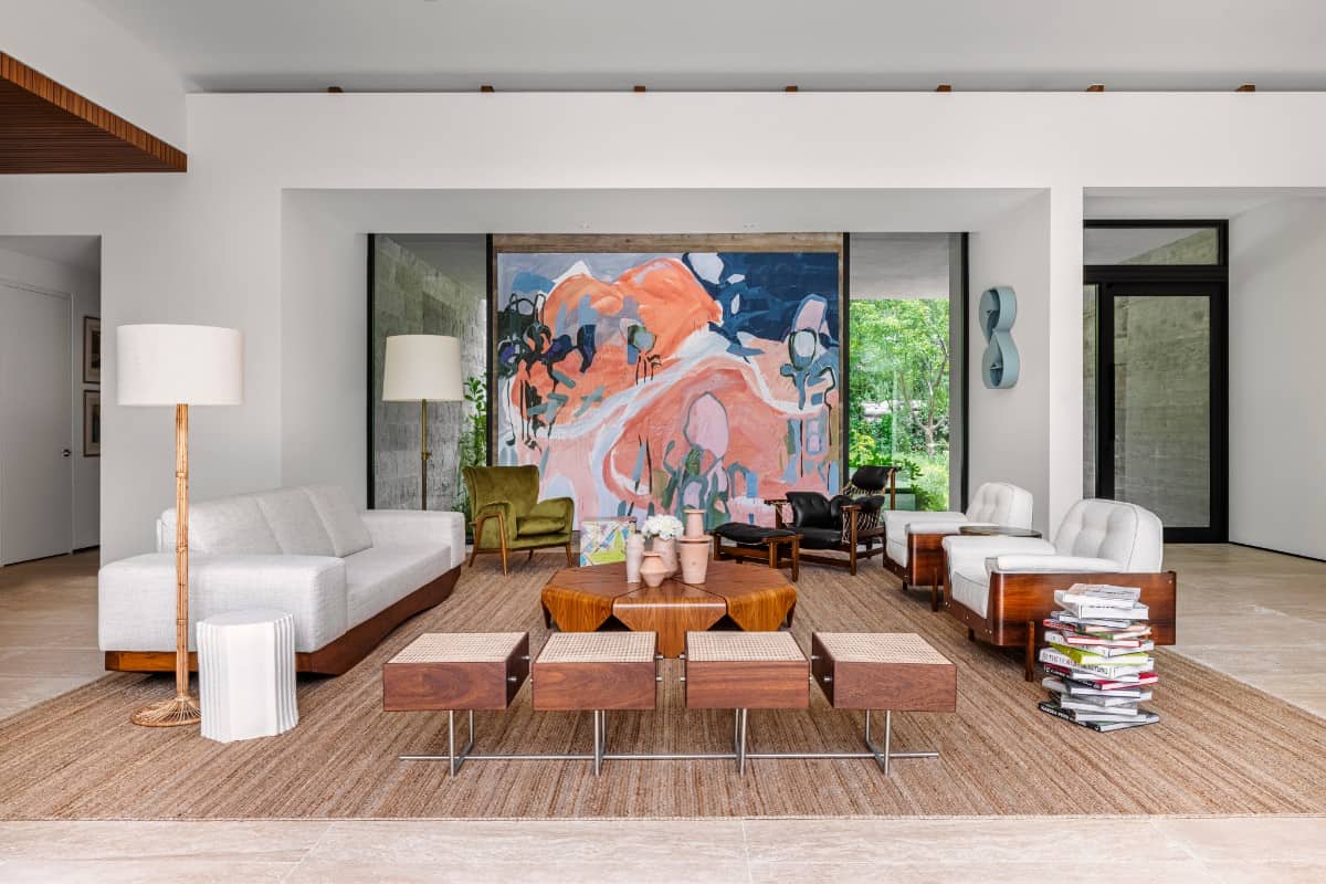 Another view of the living room, which features a Janaina Tschรคpe painting, Amir Nikravan sculpture, Jorge Zalszupin coffee table, and Jean Gillon armchairs.