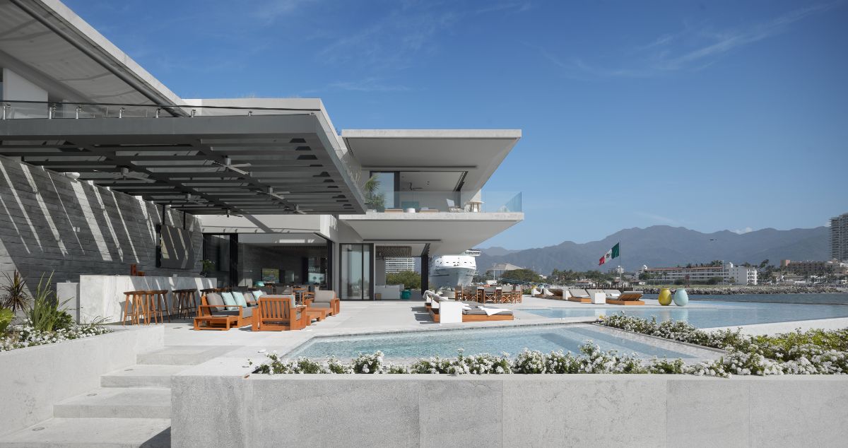 The beachfront facade of the house, with features designed to allow family and friends to enjoy a variety of activities, such as a pool with a terrace, a fireplace, a living room, and a dining room.