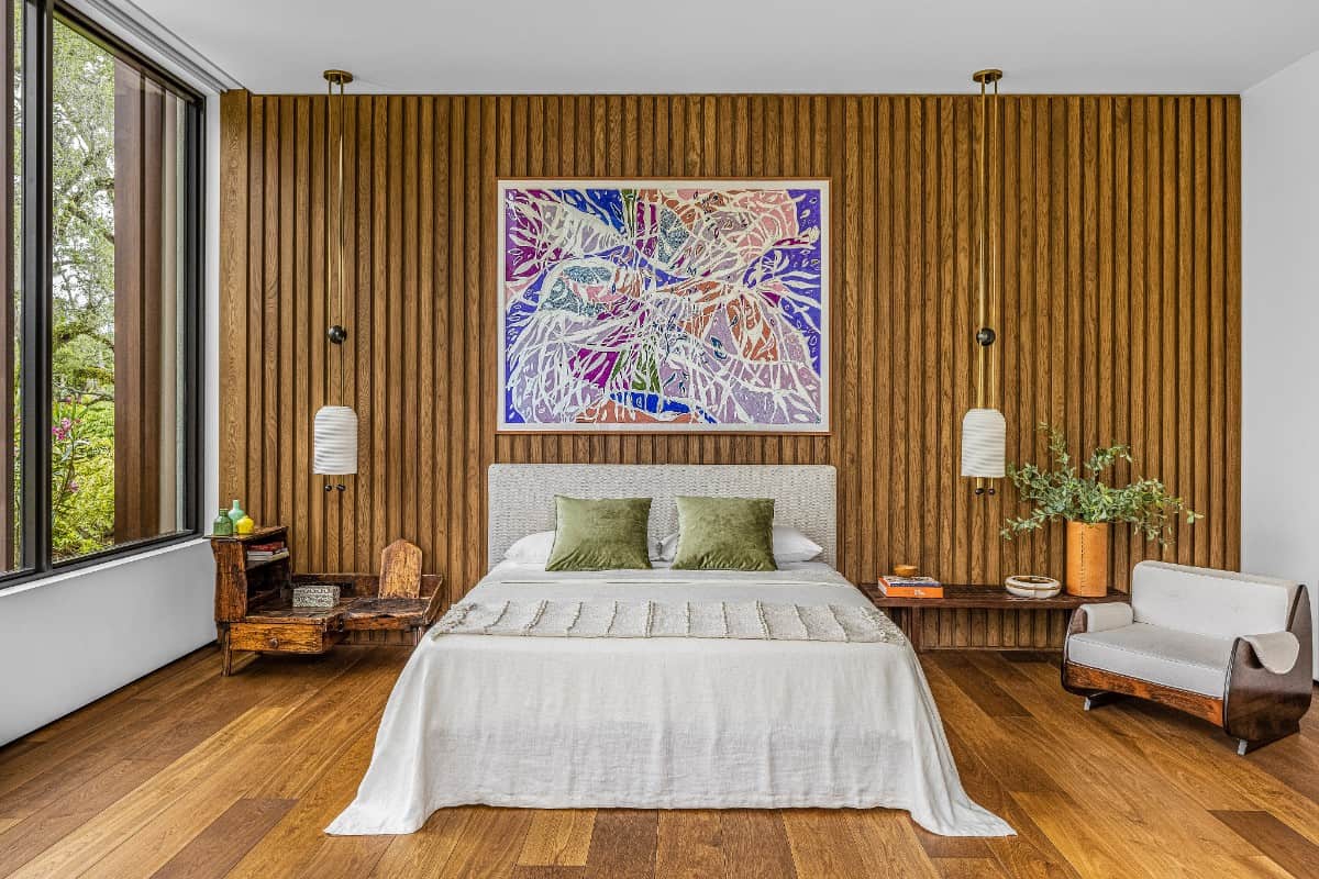 In the primary bedroom, light fixtures are by Apparatus Studio and the painting is by Marcia de Moraes; George Nelson benches serve as bedside tables.