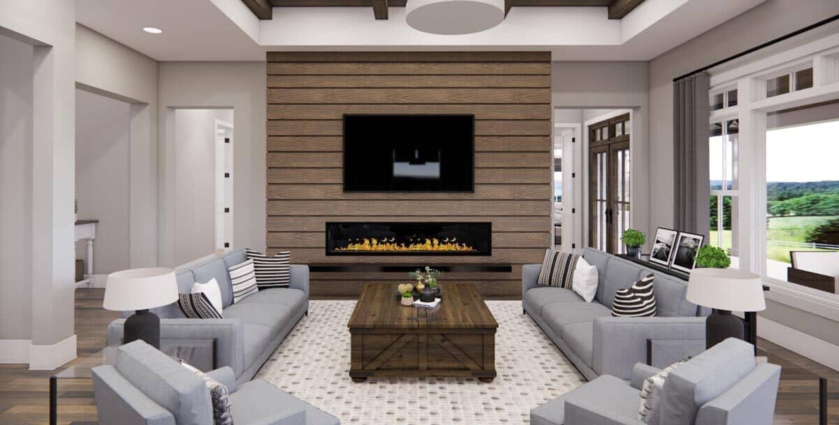 Great room with gray seats, a rustic coffee table, and a TV mounted above the fireplace.