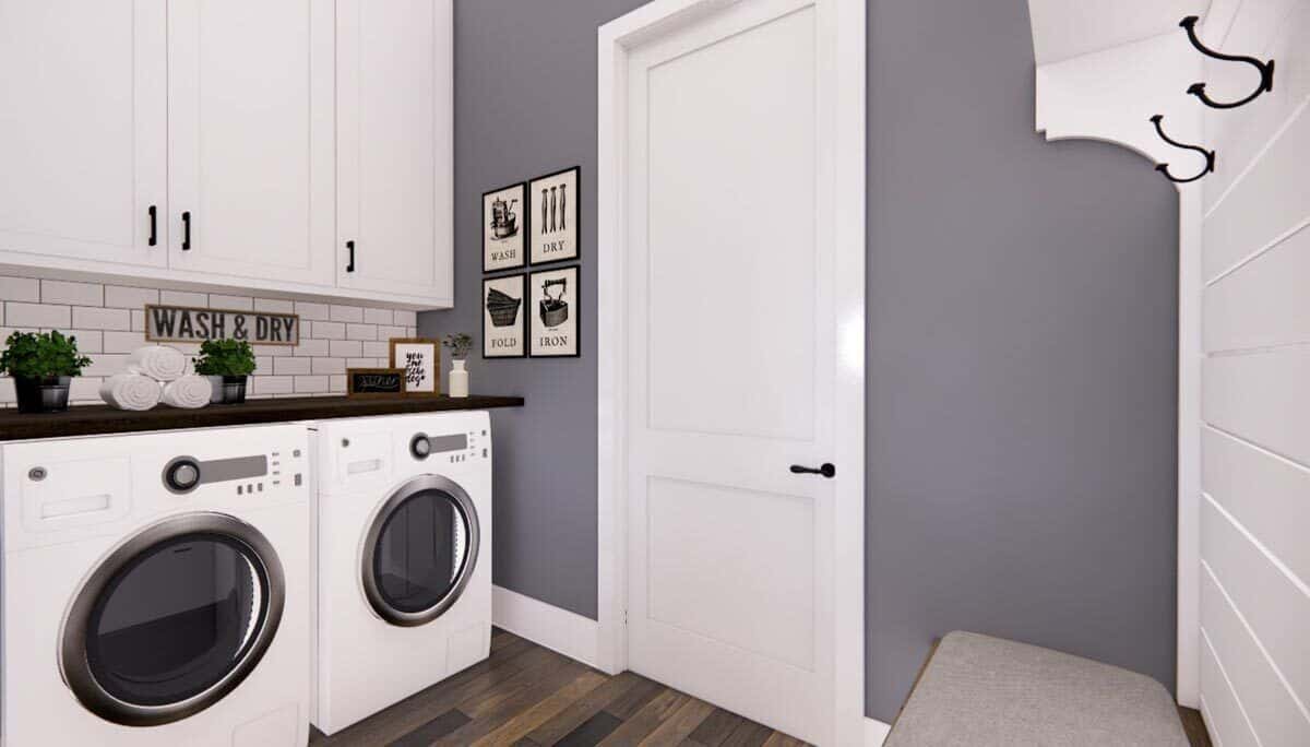 Laundry room with overhead cabinets, white appliances, and a cushioned bench.