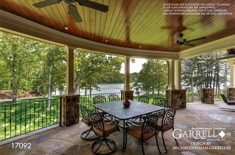 The vaulted porch spans through the outdoor dining crowned with a wood-paneled ceiling.