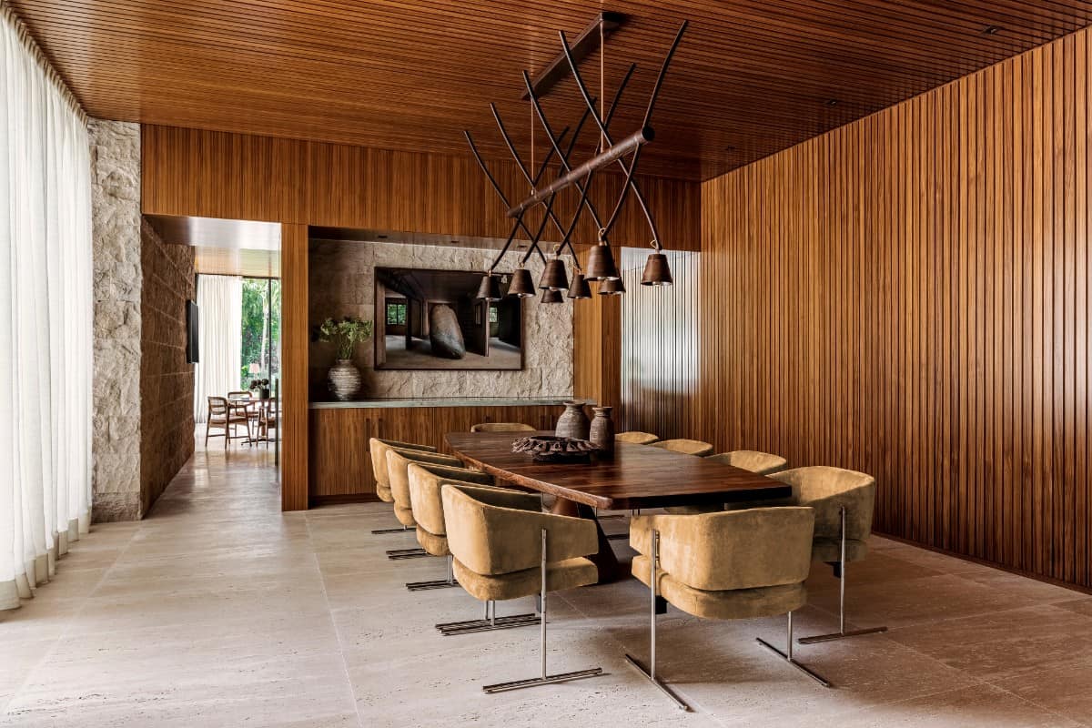 While the home's palette is predominantly earth-tone, abundant teak paneling, as seen here in the dining room, provides pops of dramatic contrast.