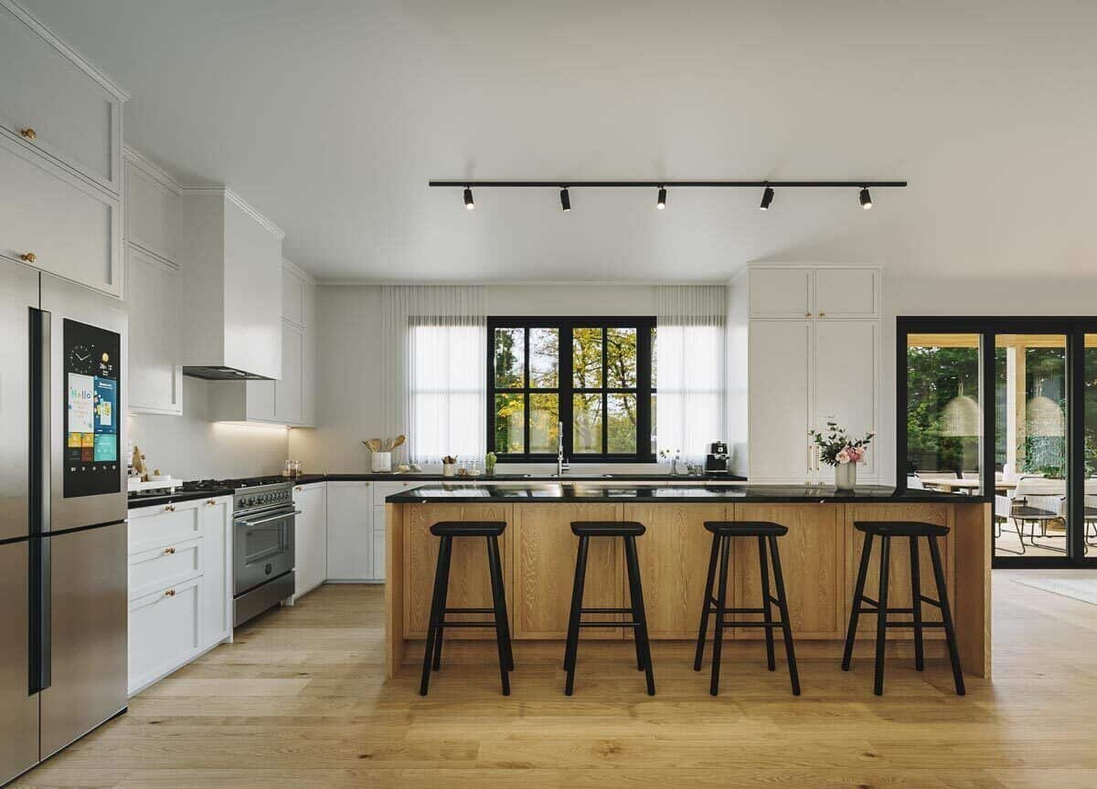 Kitchen with stainless steel appliances and an elongated island illuminated by track lights.
