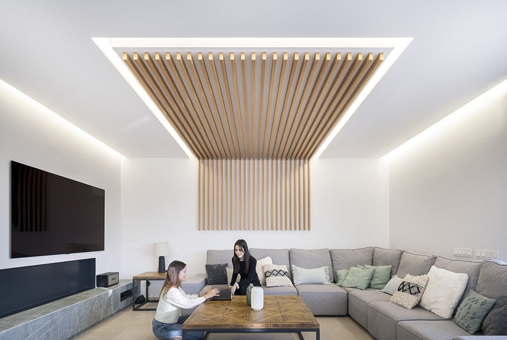 The wood slats are echoed in the living room's ceiling extending to one side of the wall.