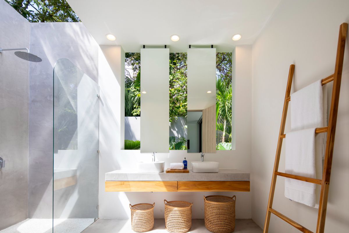 The bathroom has a neutral color scheme and an open shower. Through the windows, you can see the garden.