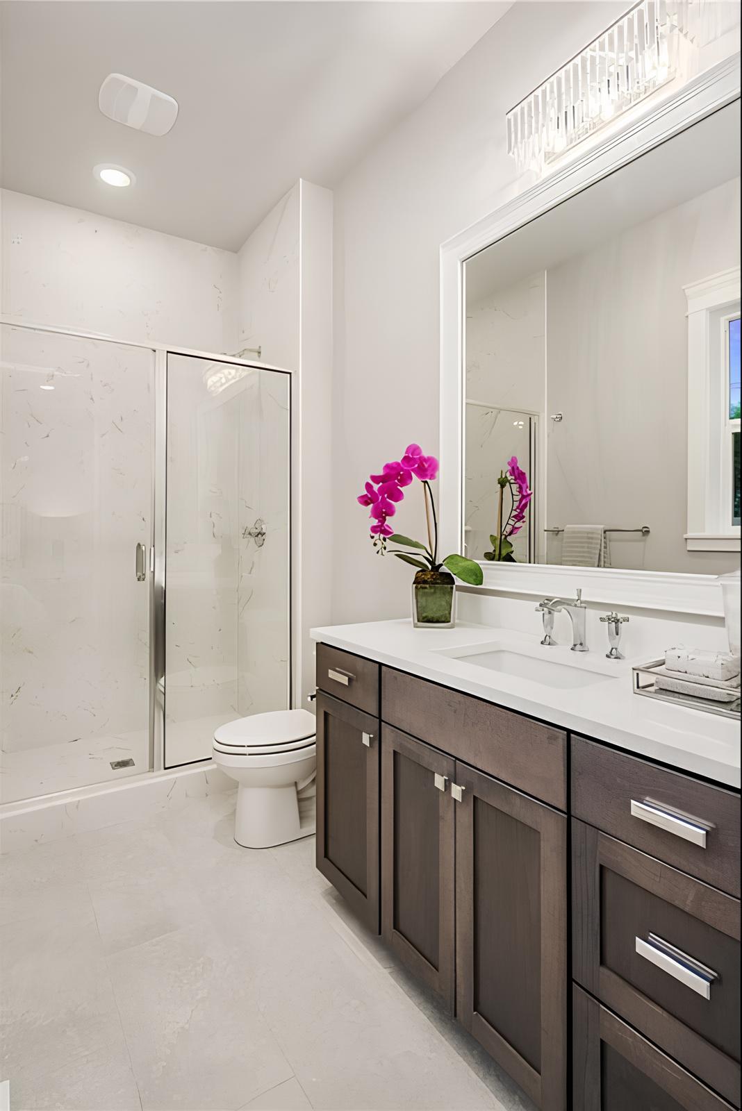 Bathroom with a wooden vanity, a toilet, and a walk-in shower enclosed in sliding glass doors.