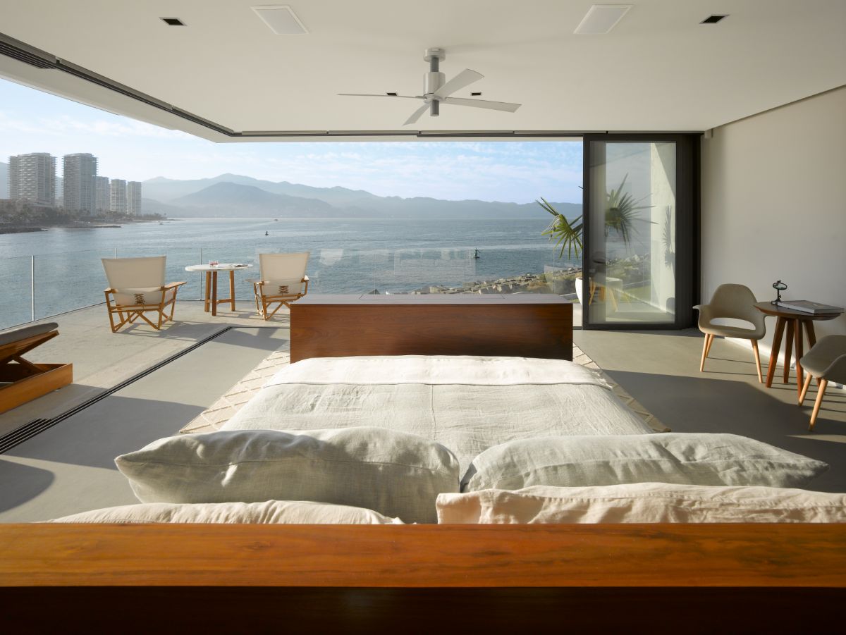 The bedroom has floor-to-ceiling windows that lead to terraces with a panoramic view of the beach.