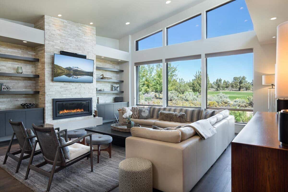 The great room offers an L-shaped sectional, cushioned armchairs, and a fireplace with a TV on top.