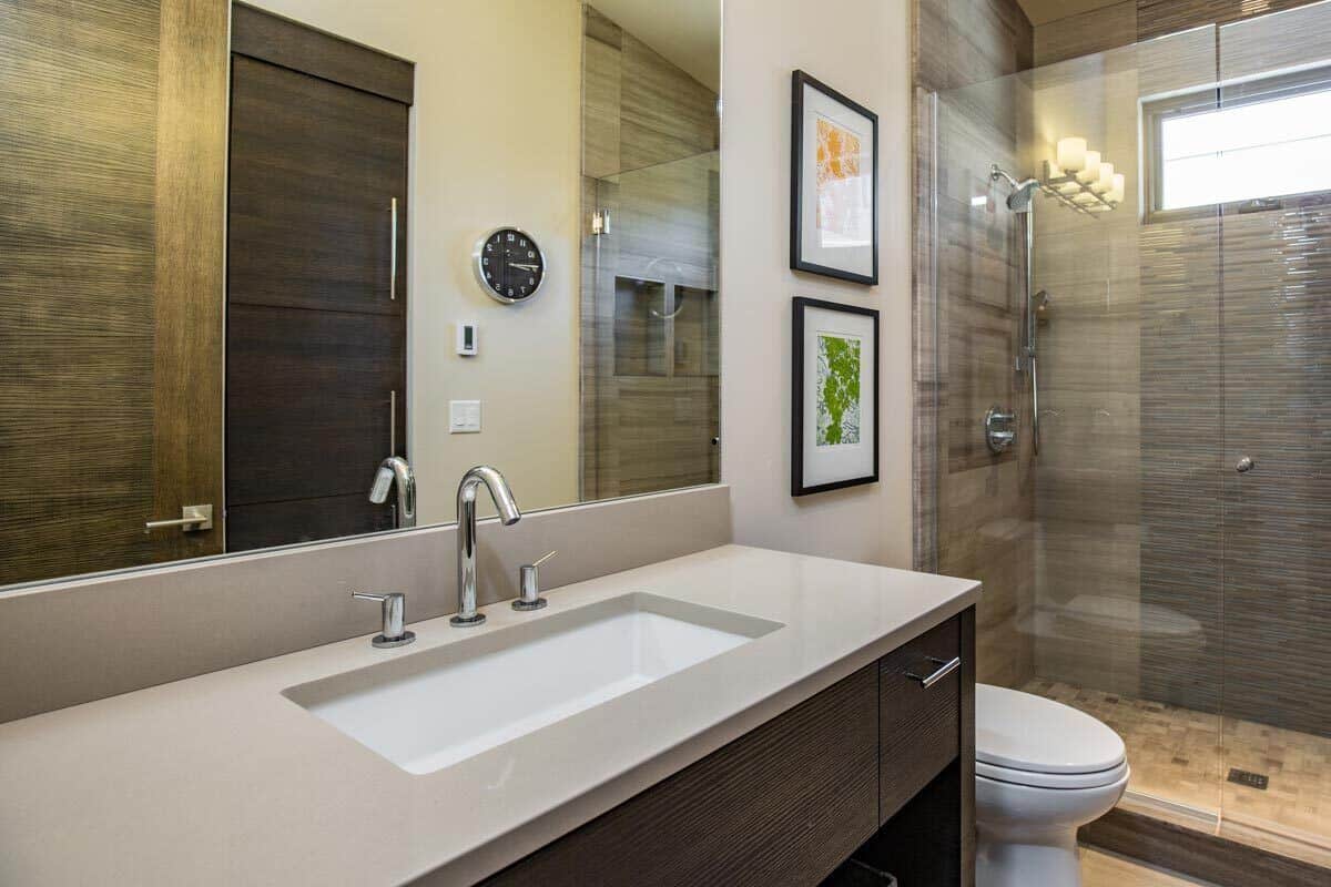 This bathroom has a single sink vanity, a toilet, and a walk-in shower brightened by a clerestory window.