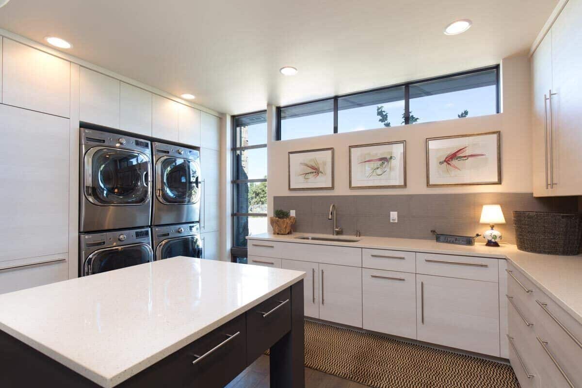 The laundry room is equipped with multiple washers and dryers, quartz countertops, a utility sink, and a center island.