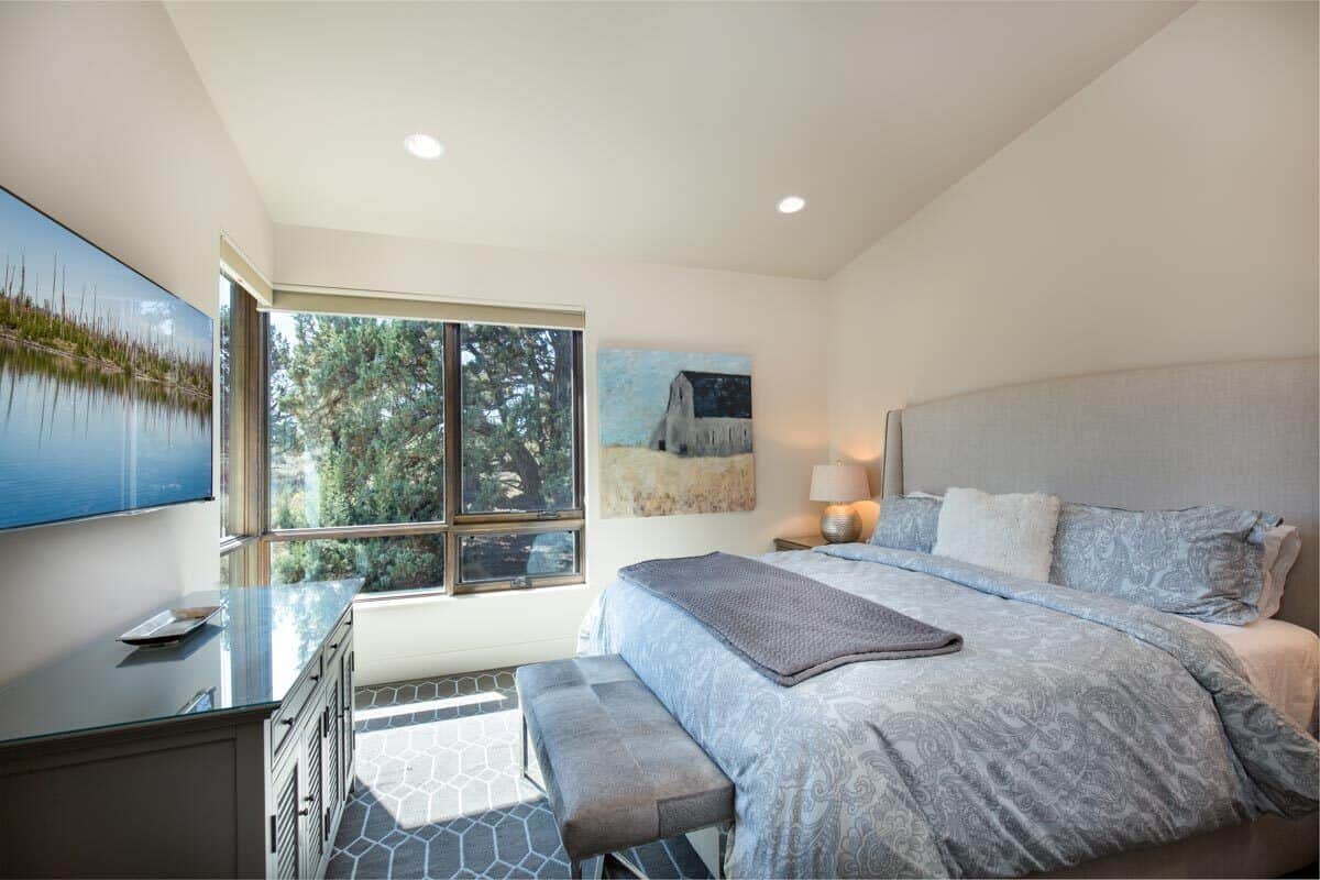 The second bedroom has a large TV and an upholstered bed over the carpeted floor.