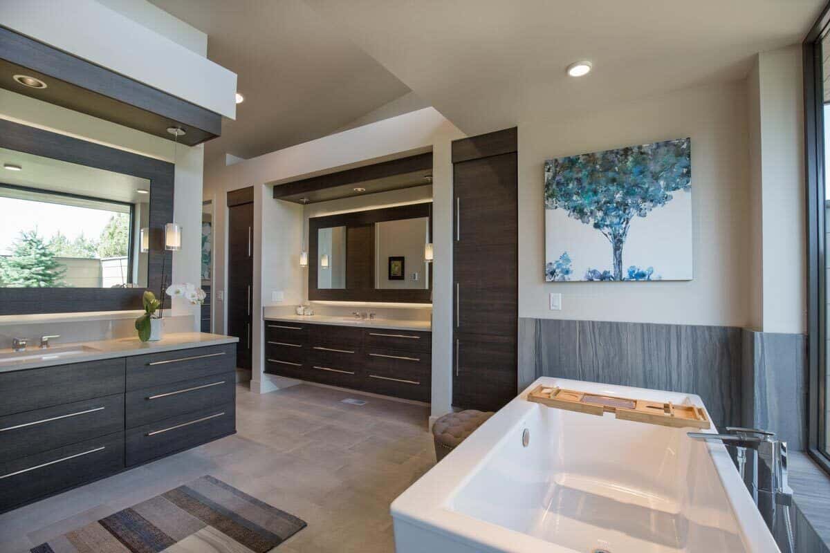 The bathroom includes separate his and her sink vanities with illuminating mirrors and wooden cabinets.
