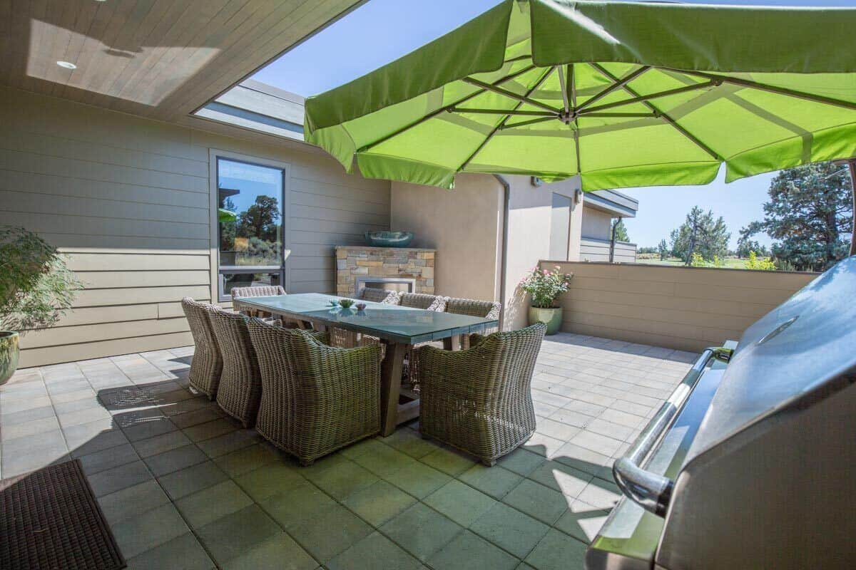 The outdoor living is filled with a wicker dining set, a built-in grill, and a corner fireplace.