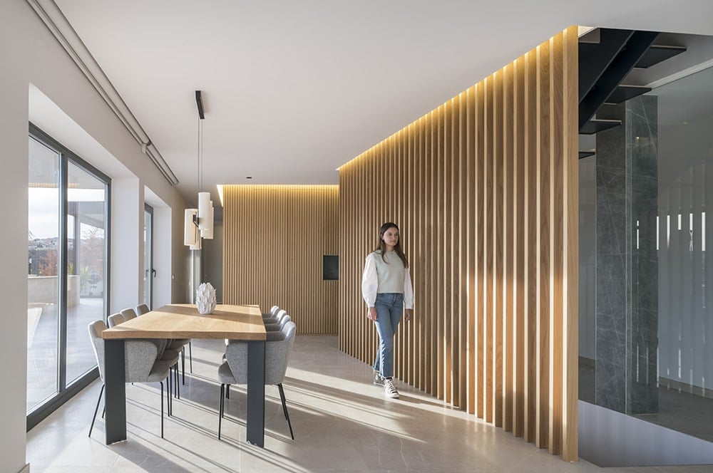 The dining area is surrounded by wood slat walls and sliding glass doors that open onto the terrace.